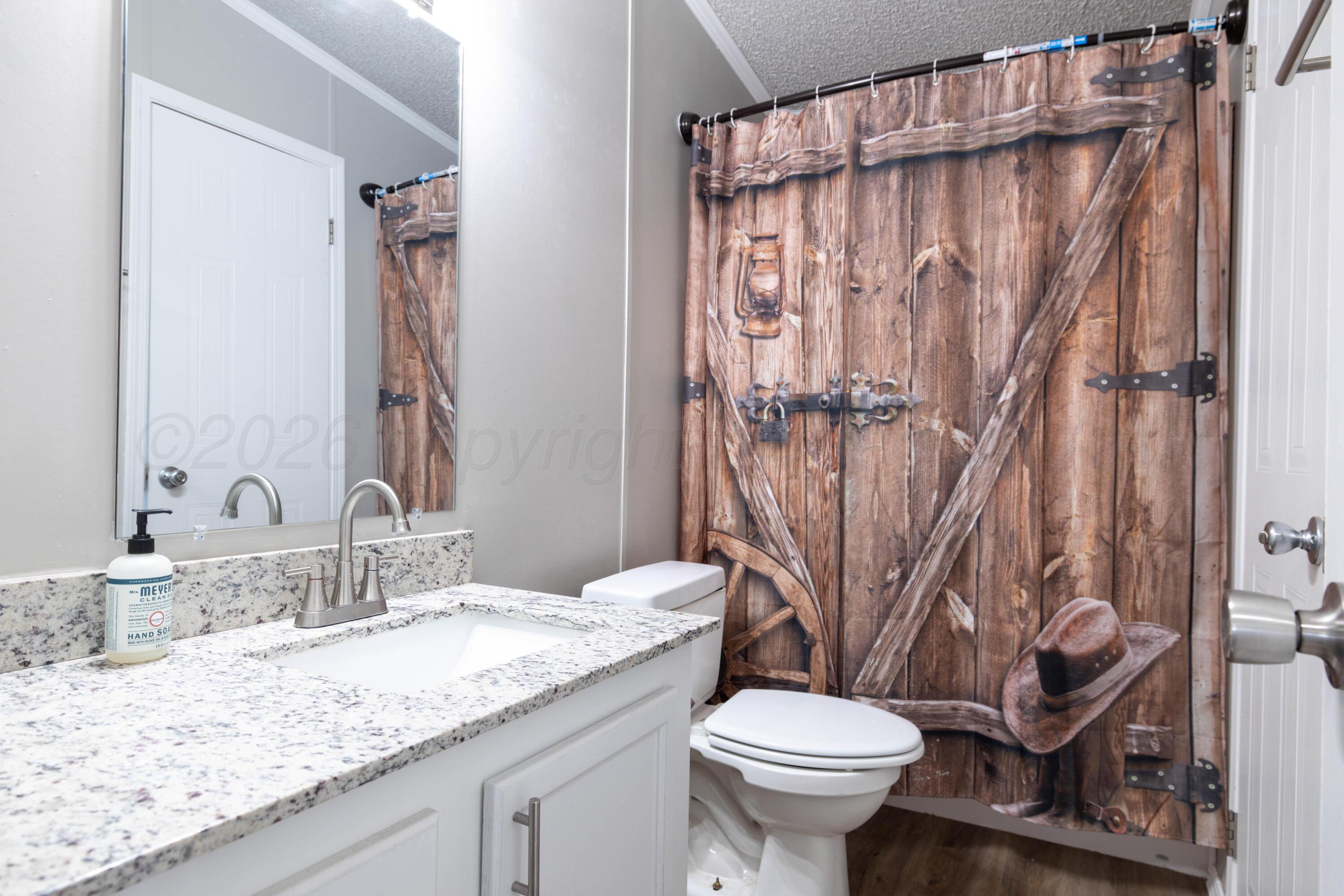 5410 Tranquility Road Amarillo, TX 79118 - Photo 29 of 37 a bathroom with a granite countertop sink toilet and a mirror
