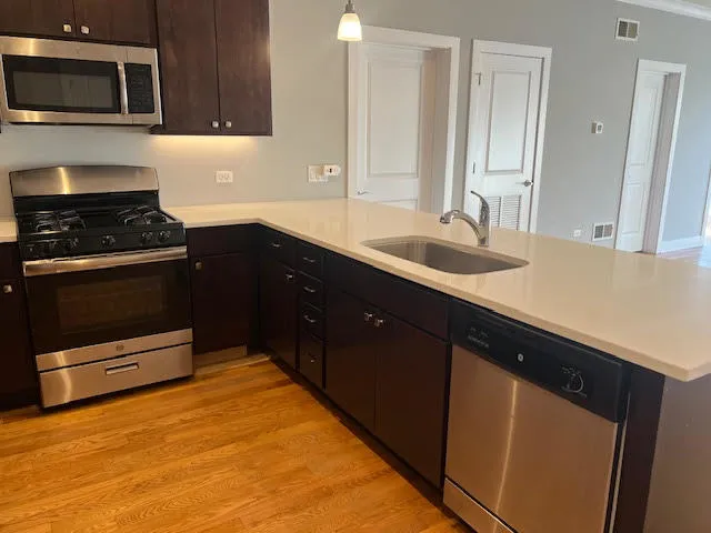 a kitchen with a sink and a stove with wooden floor