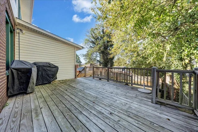 a view of a deck with wooden floor and fence with a large tree