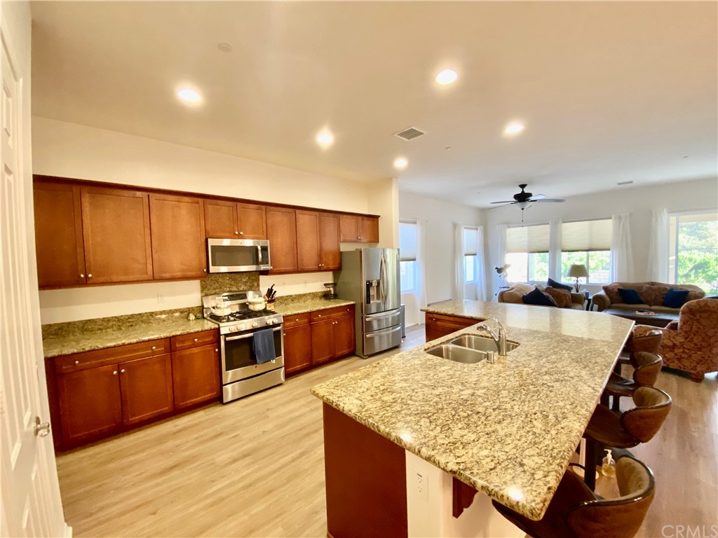 1563 Savannah Creek Beaumont, CA 92223 - Photo 7 of 28 a large kitchen with kitchen island a sink stove and wooden cabinets