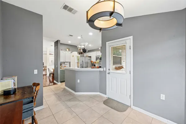 a kitchen with kitchen island a stove a refrigerator a sink a dining table and chairs with wooden floor