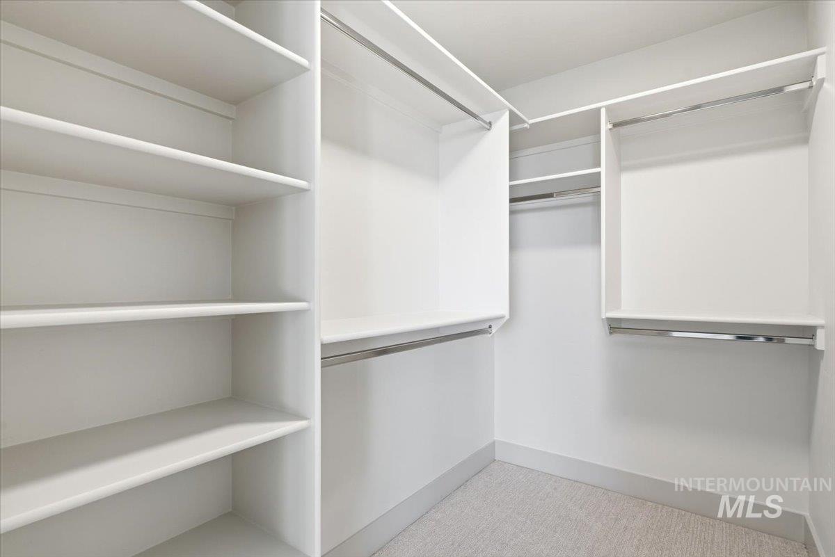 6762 South Messner Way Meridian, ID 83642 - Photo 32 of 35 Walk-in closet featuring white built-in shelving, multiple hanging rods, and light-colored carpet flooring