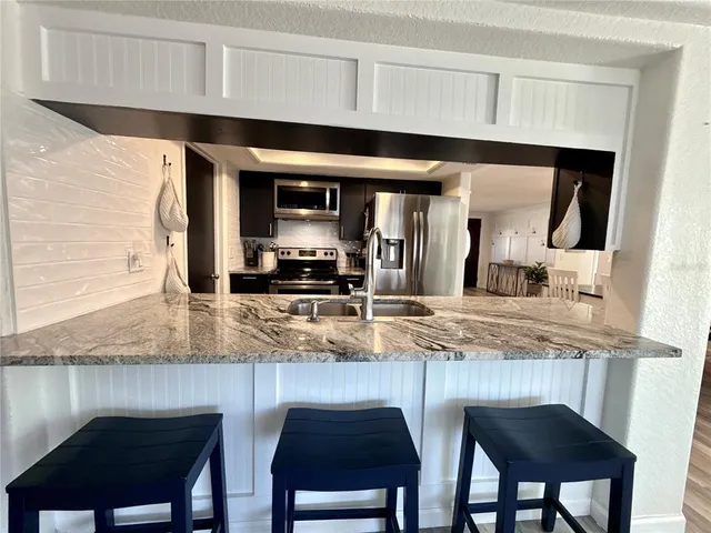 a kitchen with stainless steel appliances granite countertop a sink and a refrigerator