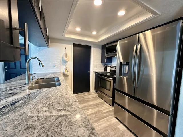 a kitchen with stainless steel appliances granite countertop a refrigerator sink and stove