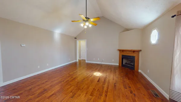 a view of an empty room with window and wooden floor