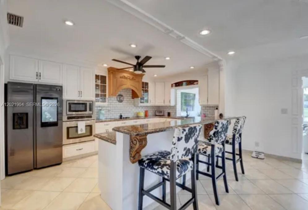 3324 Lakeview Boulevard Delray Beach, FL 33445 - Photo 13 of 36 a kitchen with stainless steel appliances kitchen island granite countertop a table and chairs in it