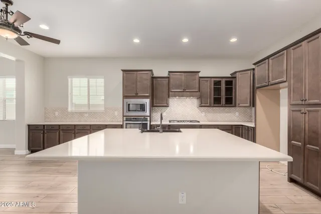 a large kitchen with kitchen island a large counter top space appliances and cabinets