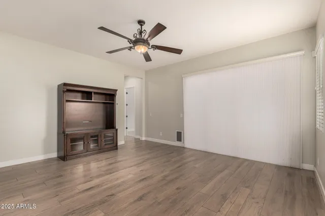 a view of an empty room with a window and wooden floor