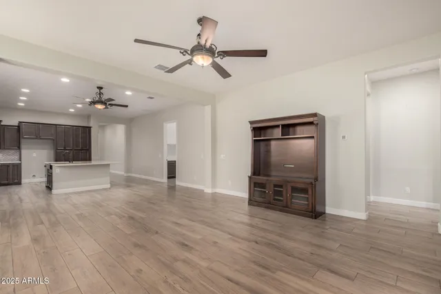 a view of empty room with wooden floor and ceiling fan