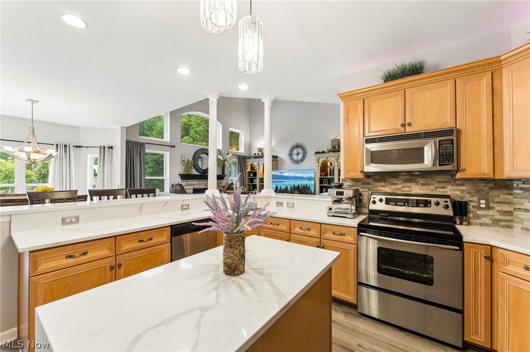 8874 Sharp Road Olmsted Falls, OH 44138 - Photo 12 of 42 Kitchen featuring a central island with a white patterned countertop, light wood cabinetry, stainless steel appliances, and a tiled backsplash