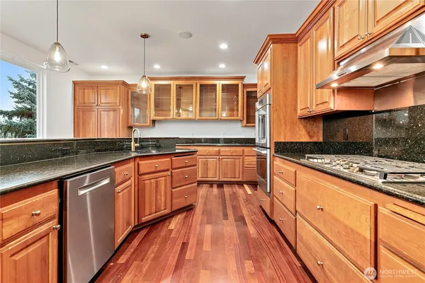 a view of a kitchen with kitchen island stainless steel appliances sink and wooden floor
