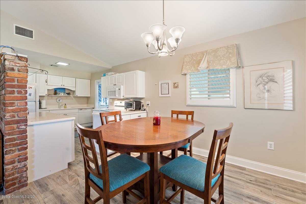 650 Java Road Cocoa Beach, FL 32931 - Photo 23 of 39 a dining room with wooden floor a chandelier a wooden table and chairs