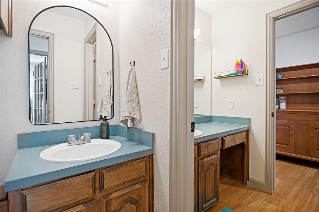 5643 West Caylor Road Fort Worth, TX 76244 - Photo 25 of 37 Bathroom vanity featuring an oval undermount sink with chrome faucet, blue countertop, and wood-finish cabinetry