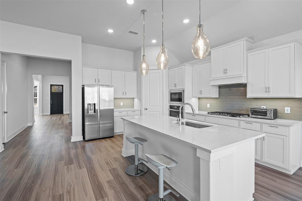 1770 English Way Waxahachie, TX 75165 - Photo 23 of 28 a kitchen with stainless steel appliances granite countertop a sink a stove a refrigerator cabinets and wooden floor