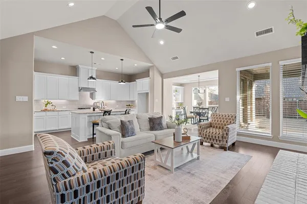 a living room with furniture kitchen view and a large window