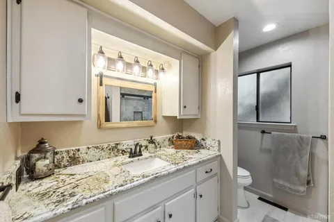 a bathroom with a granite countertop sink toilet and shower