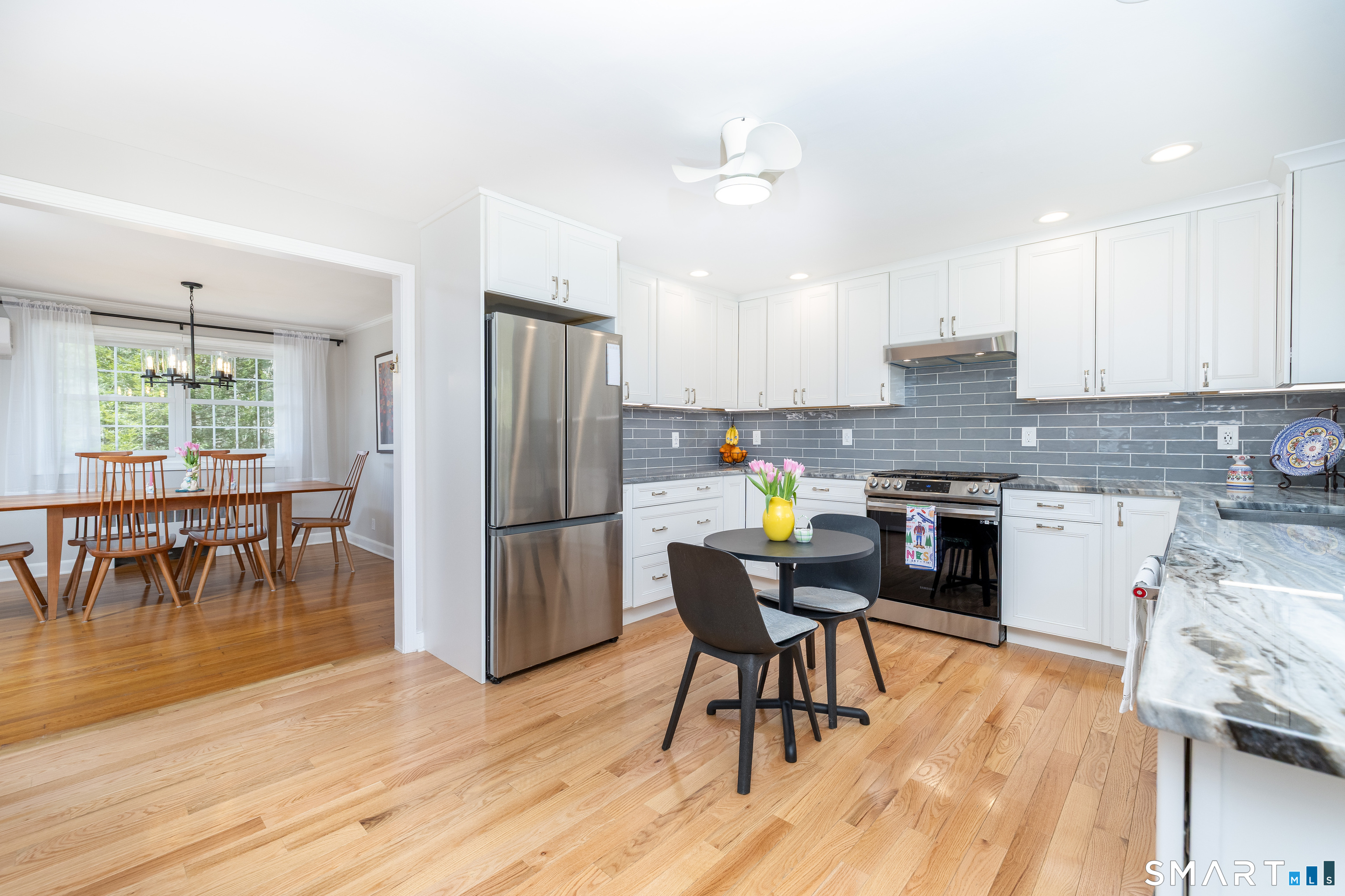 11 Sheldon Lane Litchfield, CT 06759 - Photo 7 of 33 a kitchen with stainless steel appliances granite countertop a stove a refrigerator a kitchen island a dining table and chairs with wooden floor