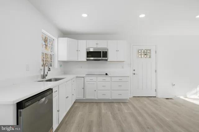 a kitchen with granite countertop white cabinets and stainless steel appliances