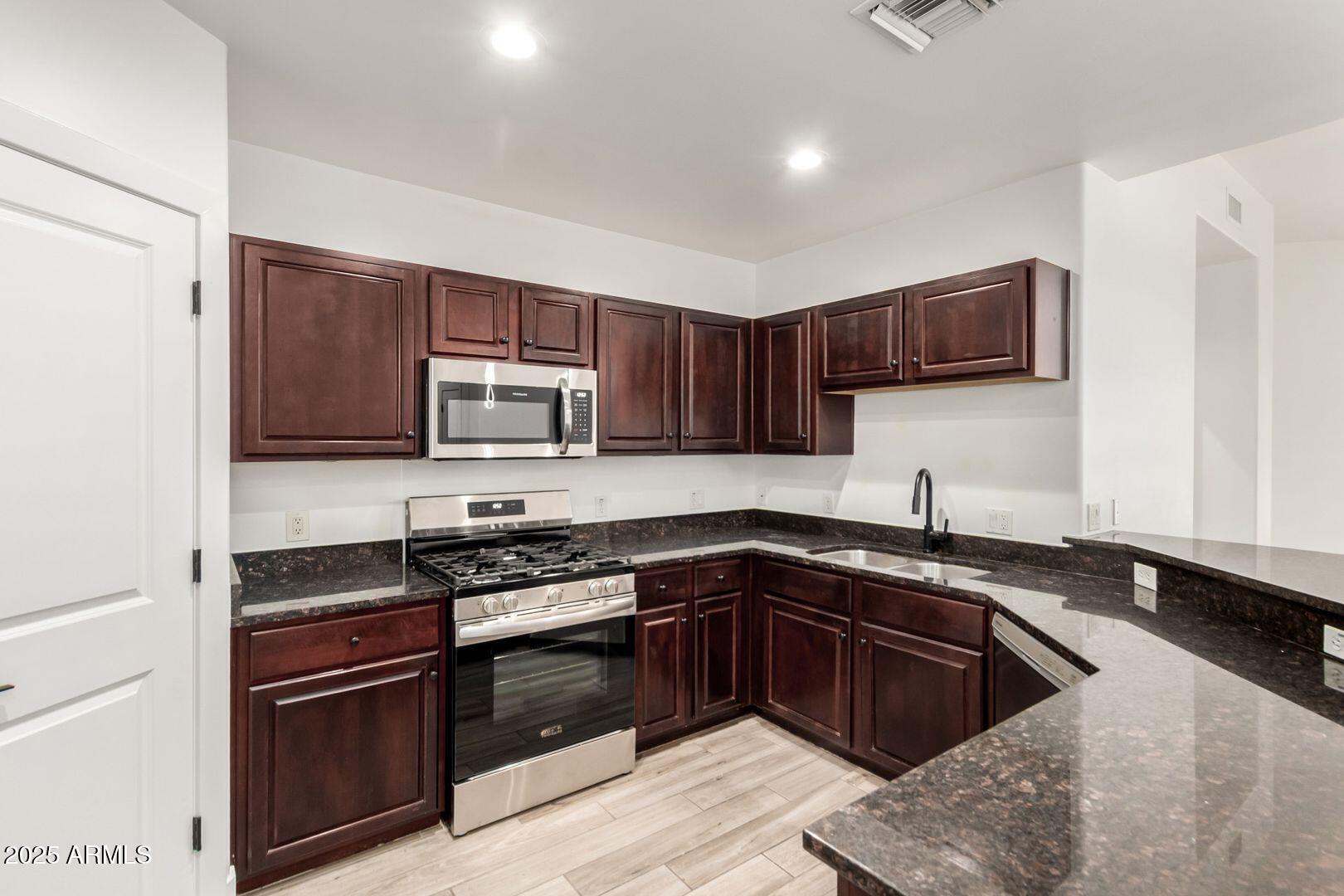 945 East Playa Del Norte Drive, Unit 4020 Tempe, AZ 85288 - Photo 12 of 39 a kitchen with stainless steel appliances granite countertop a stove microwave and sink