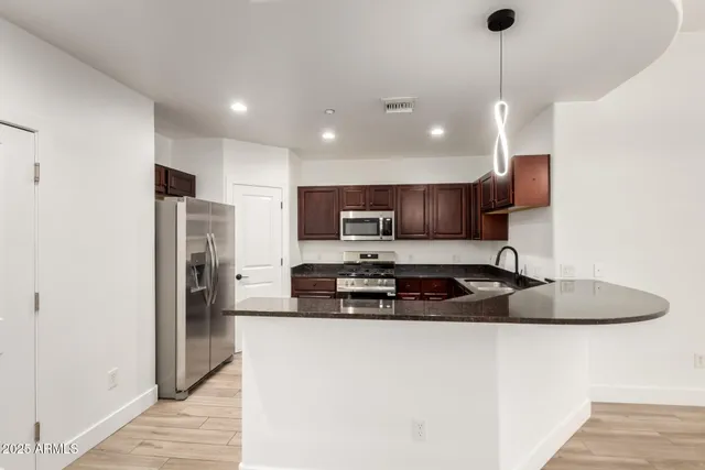 a kitchen with stainless steel appliances granite countertop a sink a refrigerator and a stove