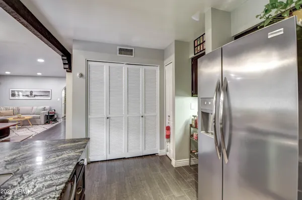 an empty room with wooden floor and a kitchen view
