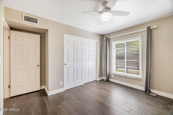 a view of empty room with wooden floor and fan