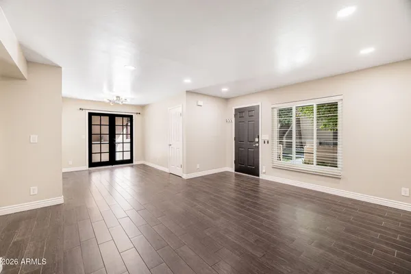 a view of an empty room with wooden floor and windows