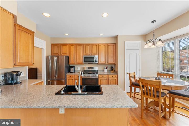 20900 Trinity Square Sterling, VA 20165 - Photo 13 of 38 a kitchen with stainless steel appliances granite countertop a stove top oven a sink a dining table and chairs with wooden floor