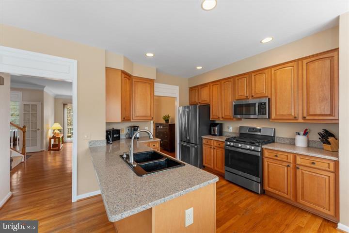 20900 Trinity Square Sterling, VA 20165 - Photo 14 of 38 a kitchen with stainless steel appliances granite countertop a stove top oven a sink dishwasher a refrigerator and cabinets with wooden floor