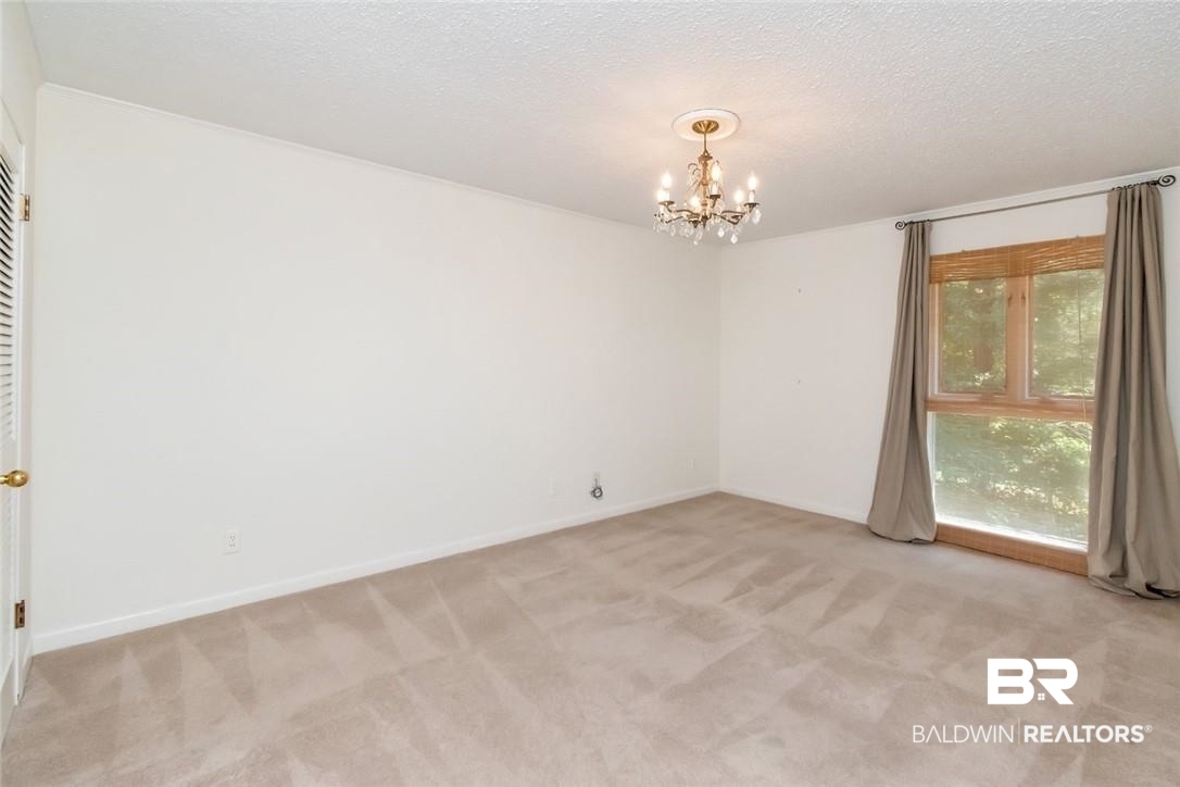 305 Fern Hill Court Mobile, AL 36608 - Photo 31 of 53 Spare room with a textured ceiling, light carpet, and a notable chandelier