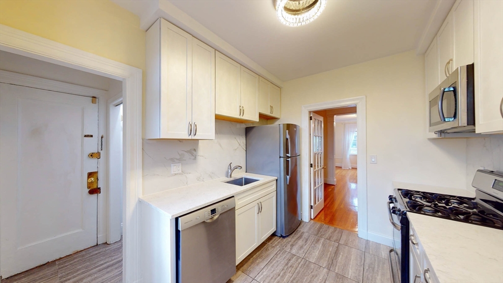 311 Tappan Street, Unit 3 Brookline, MA 02445 - Photo 14 of 35 a kitchen with stainless steel appliances granite countertop a sink stove and refrigerator