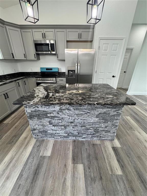 5394 Northwest 6th Place Ocala, FL 34482 - Photo 11 of 42 a kitchen with kitchen island wooden floors granite counter tops and a counter space