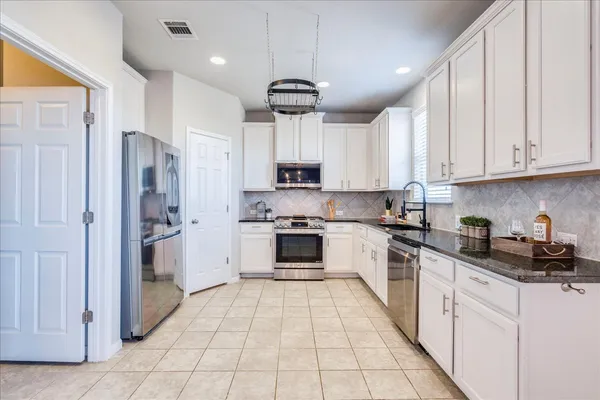 a kitchen with granite countertop white cabinets and white appliances