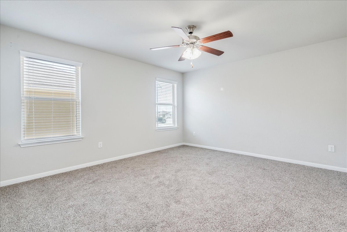 312 Triumph Road Buda, TX 78610 - Photo 23 of 37 Primary bedroom features windows providing natural light, ceiling fan and accent wall.