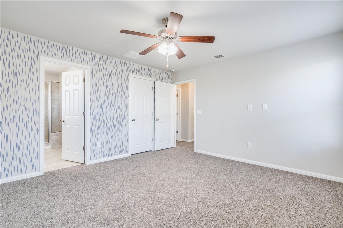 312 Triumph Road Buda, TX 78610 - Photo 25 of 37 Primary bedroom features windows providing natural light, ceiling fan and accent wall.