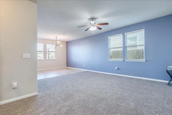 an empty room with windows and chandelier fan