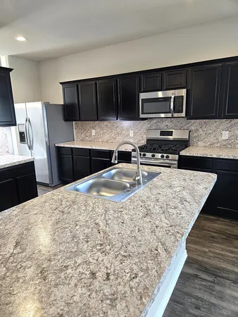 a kitchen with stainless steel appliances kitchen island granite countertop a refrigerator stove and sink