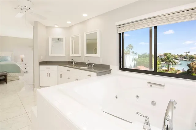 a large white bed in a room with a large window and mirror