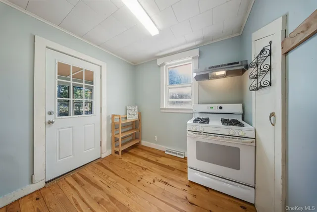 a kitchen with stove and white cabinets with wooden floor