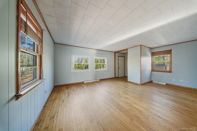 a view of an empty room with a window and wooden floor