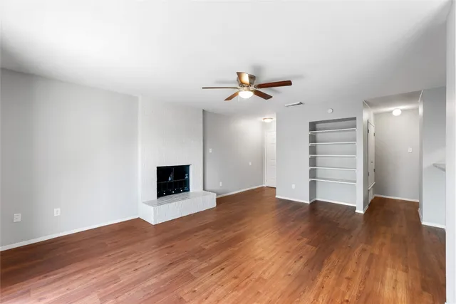 a view of an empty room with a ceiling fan and wooden floor
