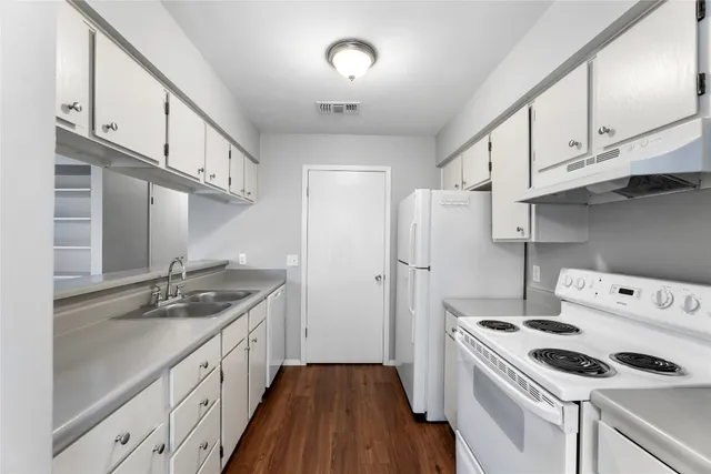 a kitchen with granite countertop a sink stove and refrigerator