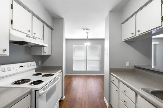 a kitchen with granite countertop a stove and a white wooden cabinets