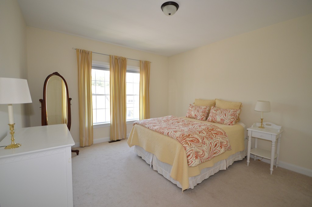 704 Autumn Ridge Drive, Unit 704 Ayer, MA 01432 - Photo 15 of 30 a bedroom with a bed a mirror and a window