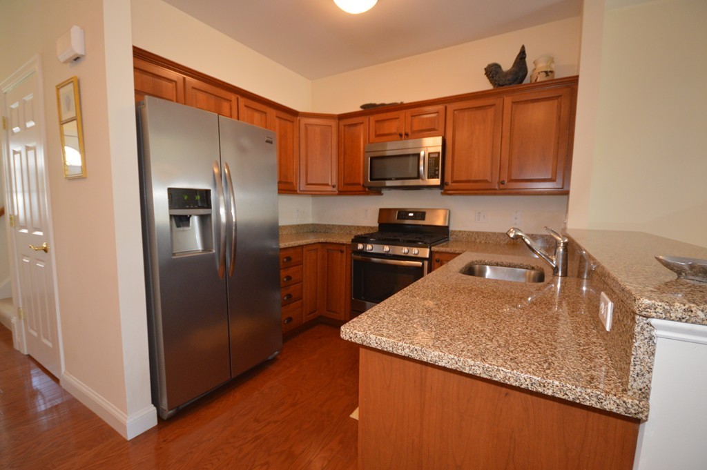 704 Autumn Ridge Drive, Unit 704 Ayer, MA 01432 - Photo 8 of 30 a kitchen with stainless steel appliances granite countertop a refrigerator a stove top oven a sink and dishwasher