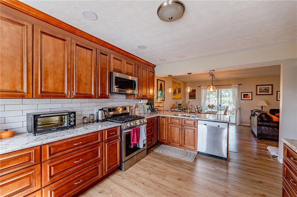 120 Lockheed Drive Coraopolis, PA 15108 - Photo 4 of 31 a large kitchen with stainless steel appliances granite countertop a stove top oven a refrigerator a sink dishwasher with wooden cabinets and wooden floor