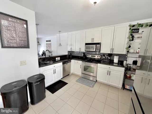 a white kitchen with granite top stainless steel appliances and sink