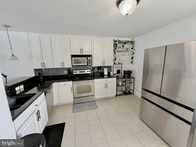 a kitchen with a refrigerator a stove and white cabinets