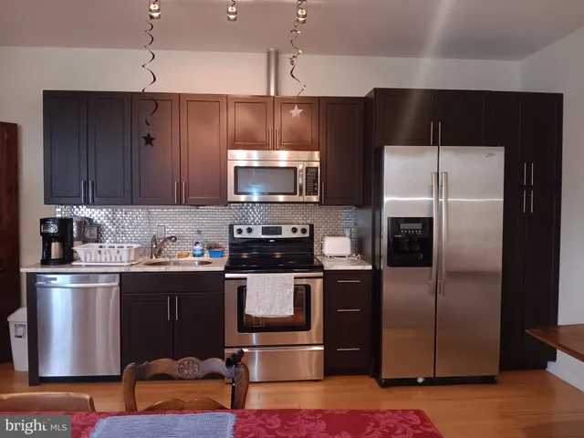 a kitchen with stainless steel appliances wooden floor and a refrigerator