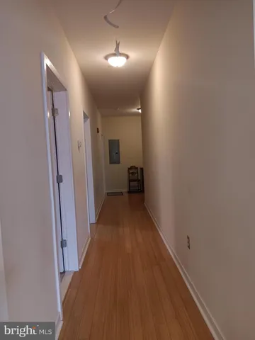 a view of a hallway with wooden floor and a bathroom